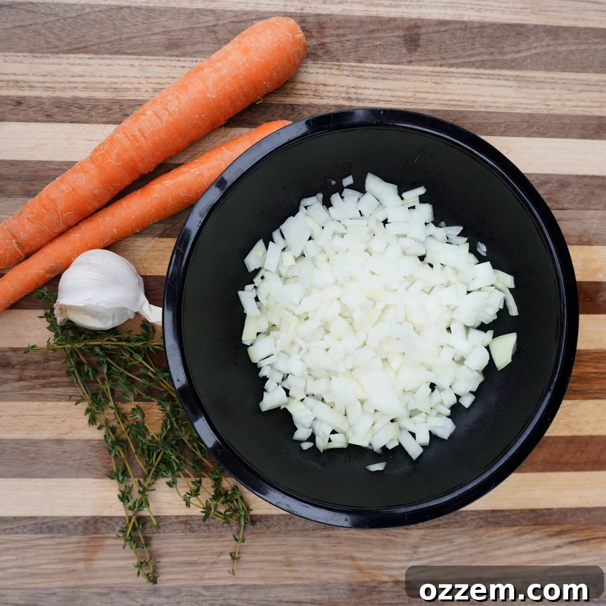 Chopped yellow onion, carrots, and minced garlic, key ingredients for the smoked meat pie gravy, arranged on a wooden cutting board.
