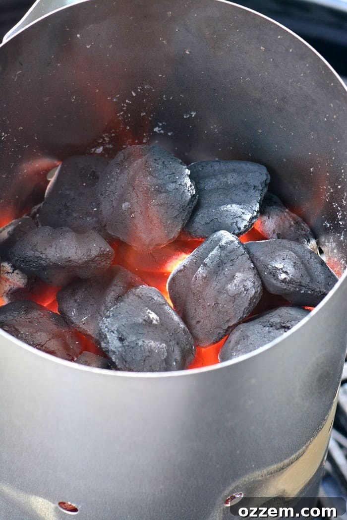 Perfectly lit coals glowing in a chimney starter, ready for grilling