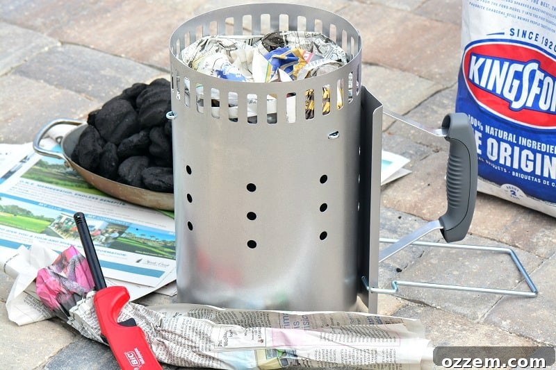 Tightly rolled newspaper being carefully placed into the bottom chamber of a chimney starter