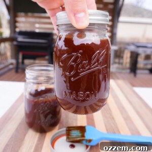 Sweet and tangy BBQ sauce in a mason jar, showcased next to a dirty brush.