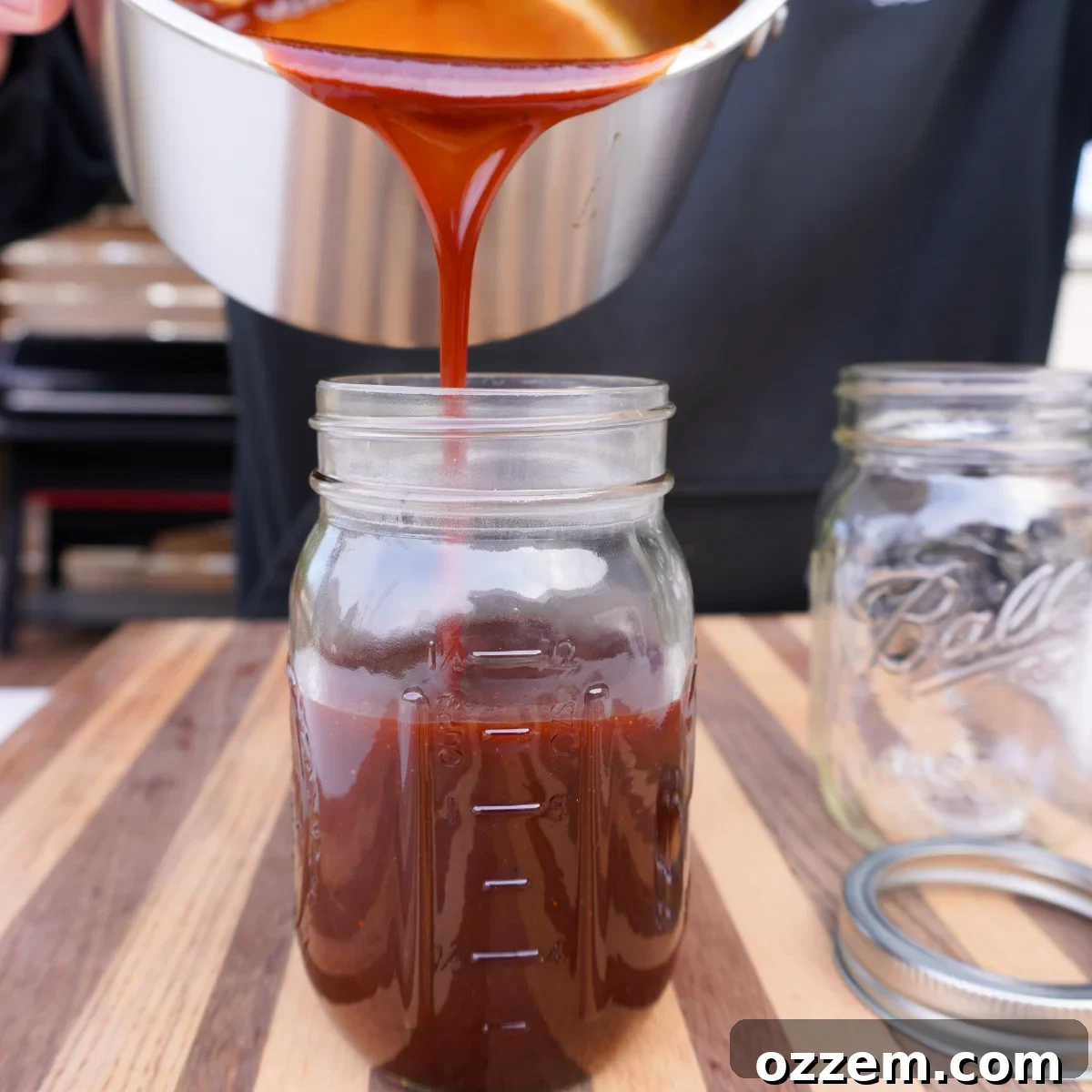 Pouring the freshly made BBQ sauce into a clean mason jar.