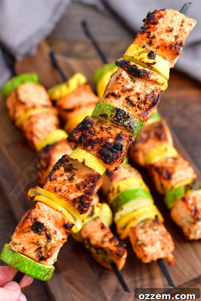 holding one long skewer of salmon and vegetables on it
