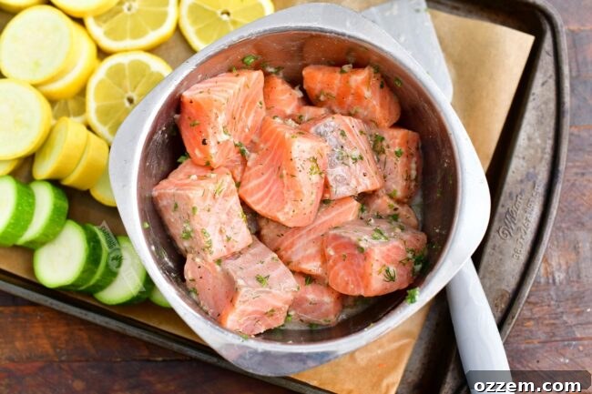 salmon pieces in a mixing bowl mixed with herbs and garlic marinade