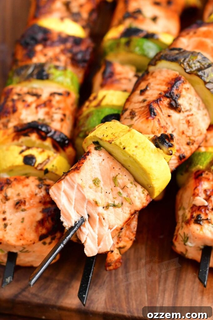plate of grilled salmon kebabs with lemon slices and herbs