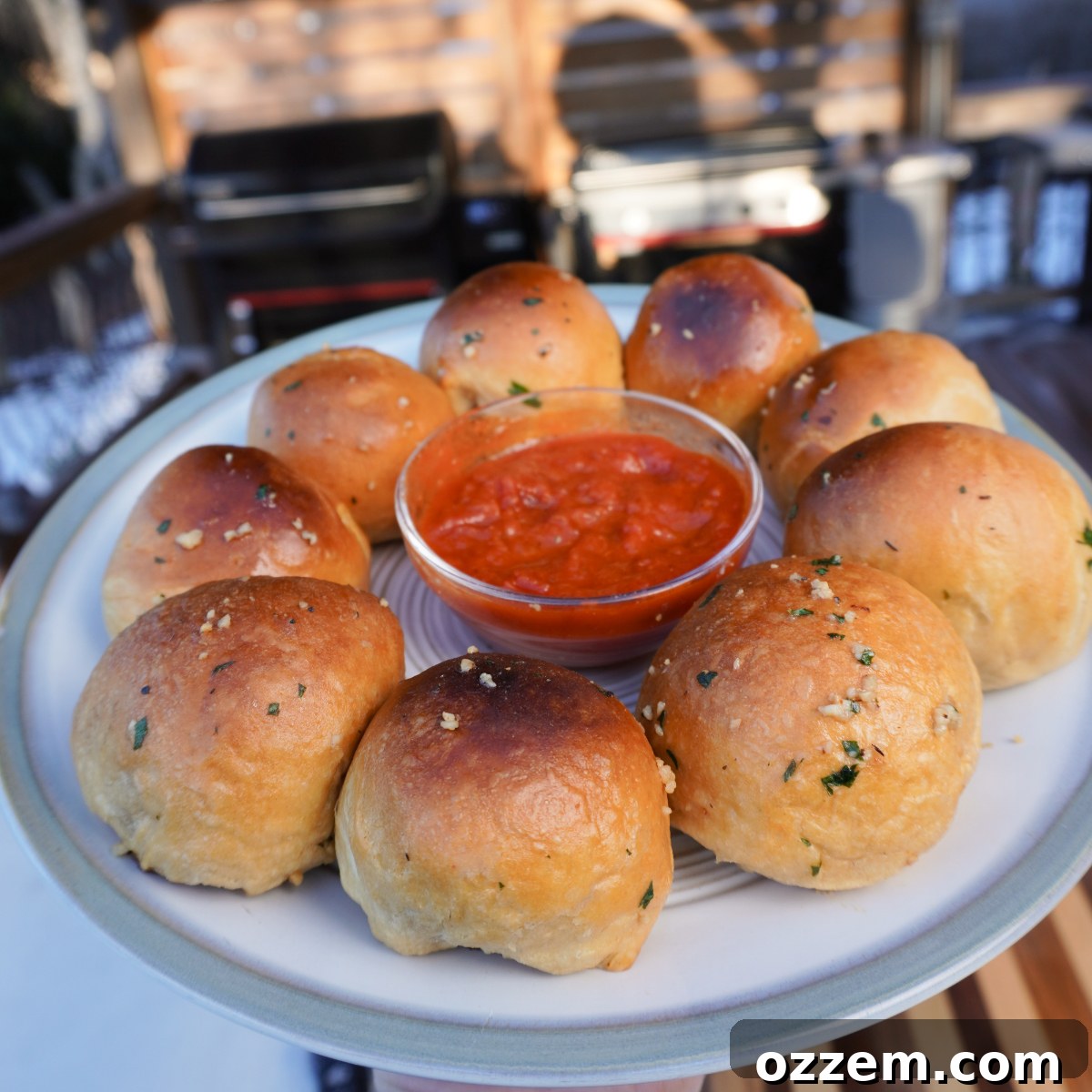 Smoked Meatball Biscuits elegantly served on a plate with a bowl of marinara sauce in the center.
