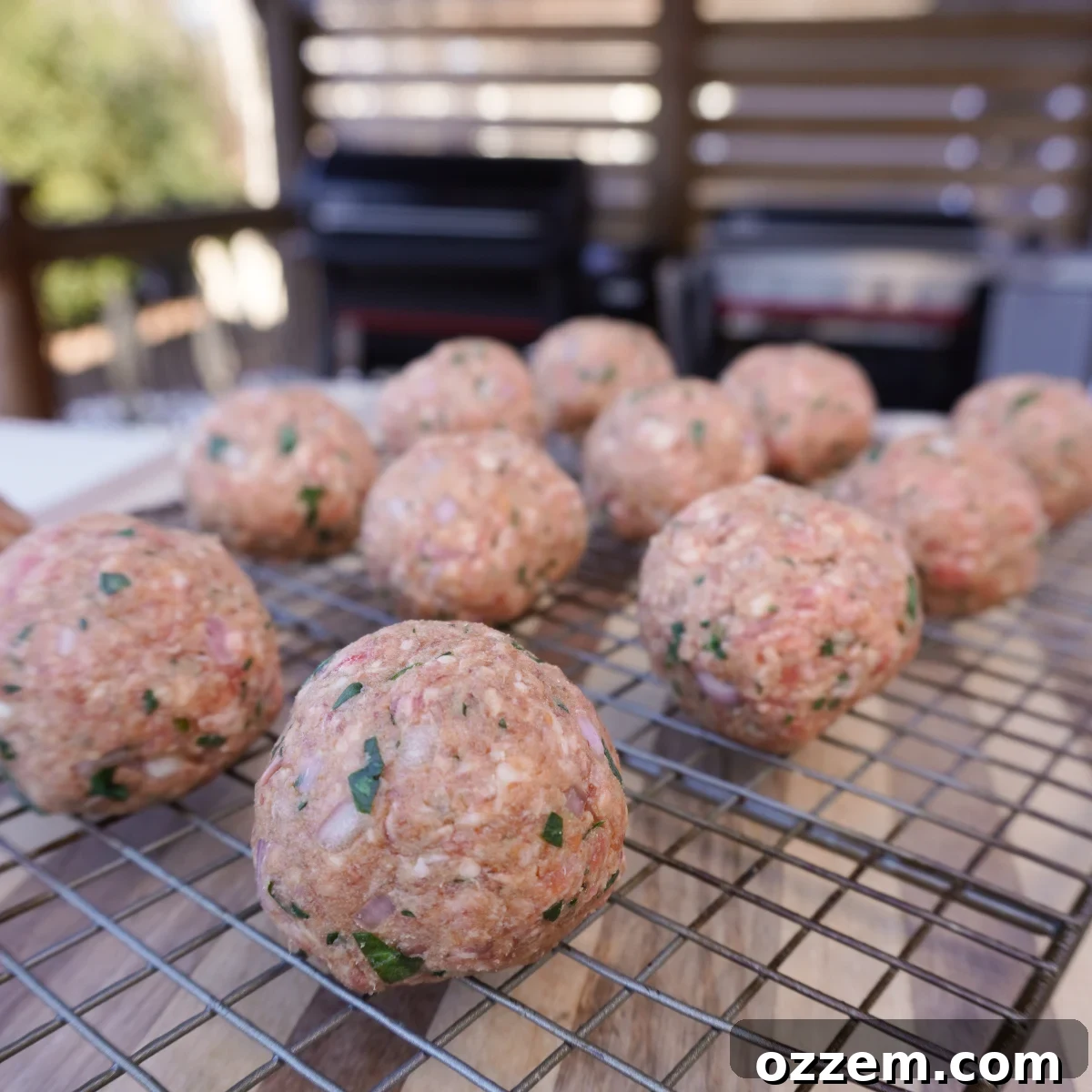 Several round, formed raw meatballs neatly arranged on a wire rack.