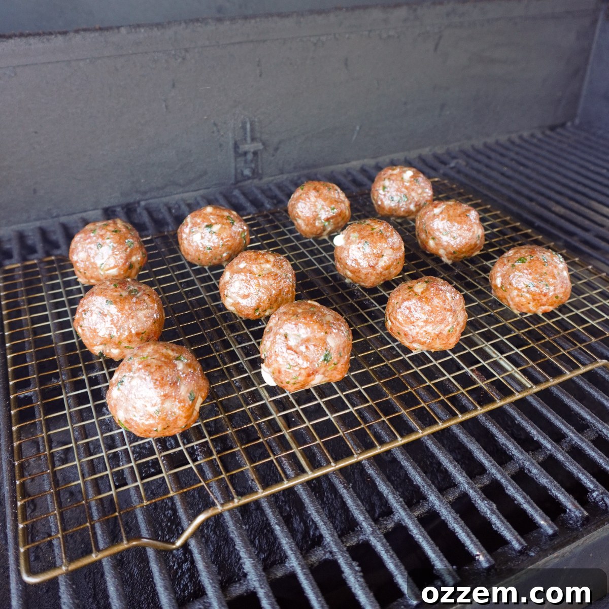 Smoked meatballs cooking on a grill, surrounded by a smoky atmosphere.