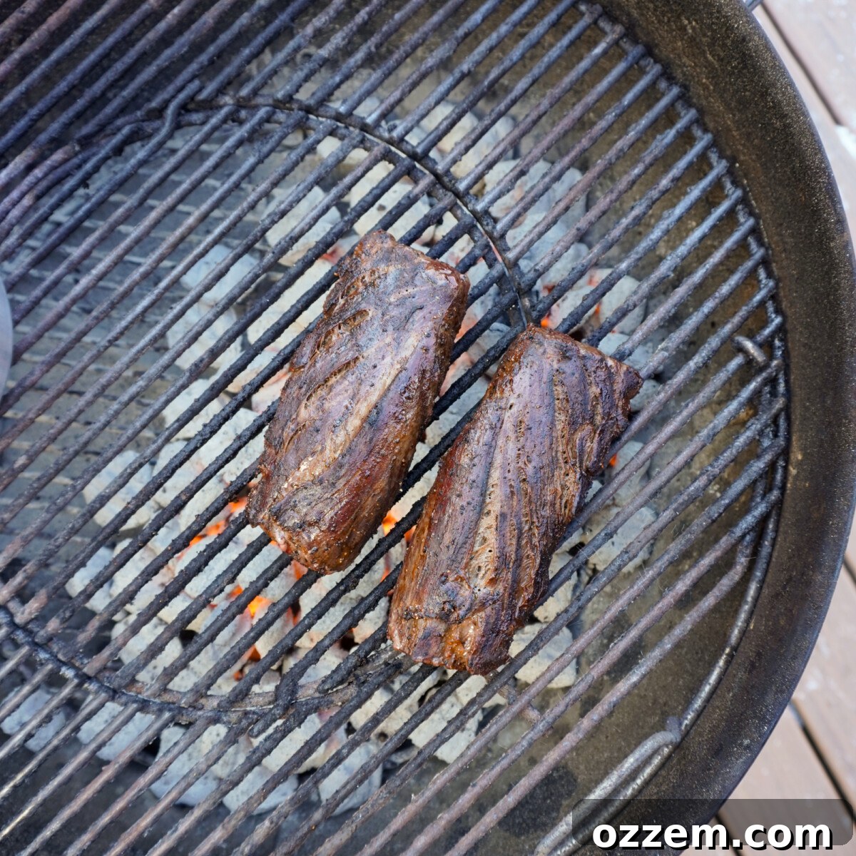 Perfectly grilled venison tenderloin searing on the hot grates of a grill, showing a beautiful crust developing.