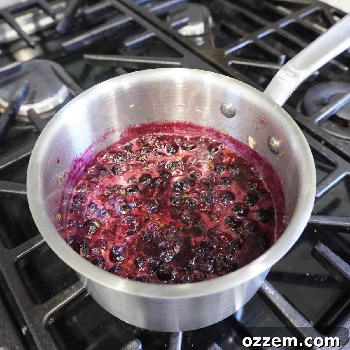 Homemade blueberry sauce simmering in a saucepan on the stove, a rich and vibrant topping.