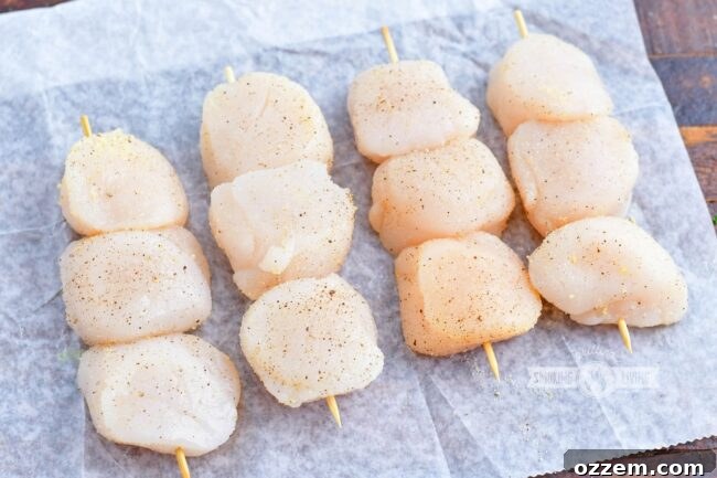 Raw scallops, patted dry and lightly oiled, seasoned with salt, pepper, and garlic powder, threaded onto wooden skewers.