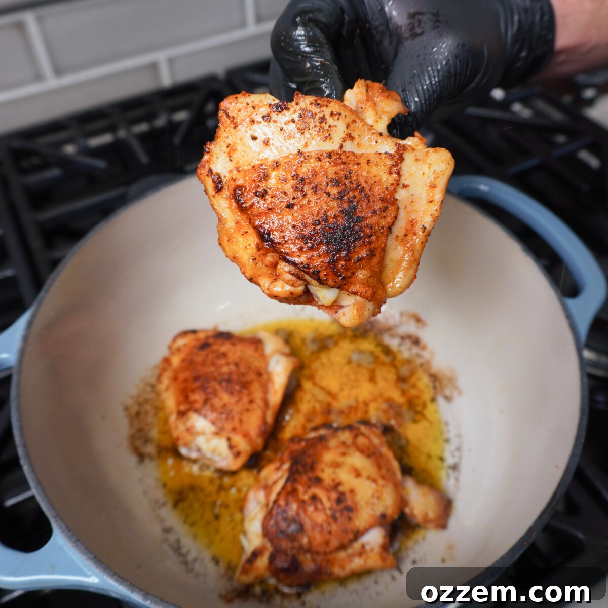 Close-up of chicken thighs searing skin-down in a Dutch oven, achieving a golden brown and crispy texture.
