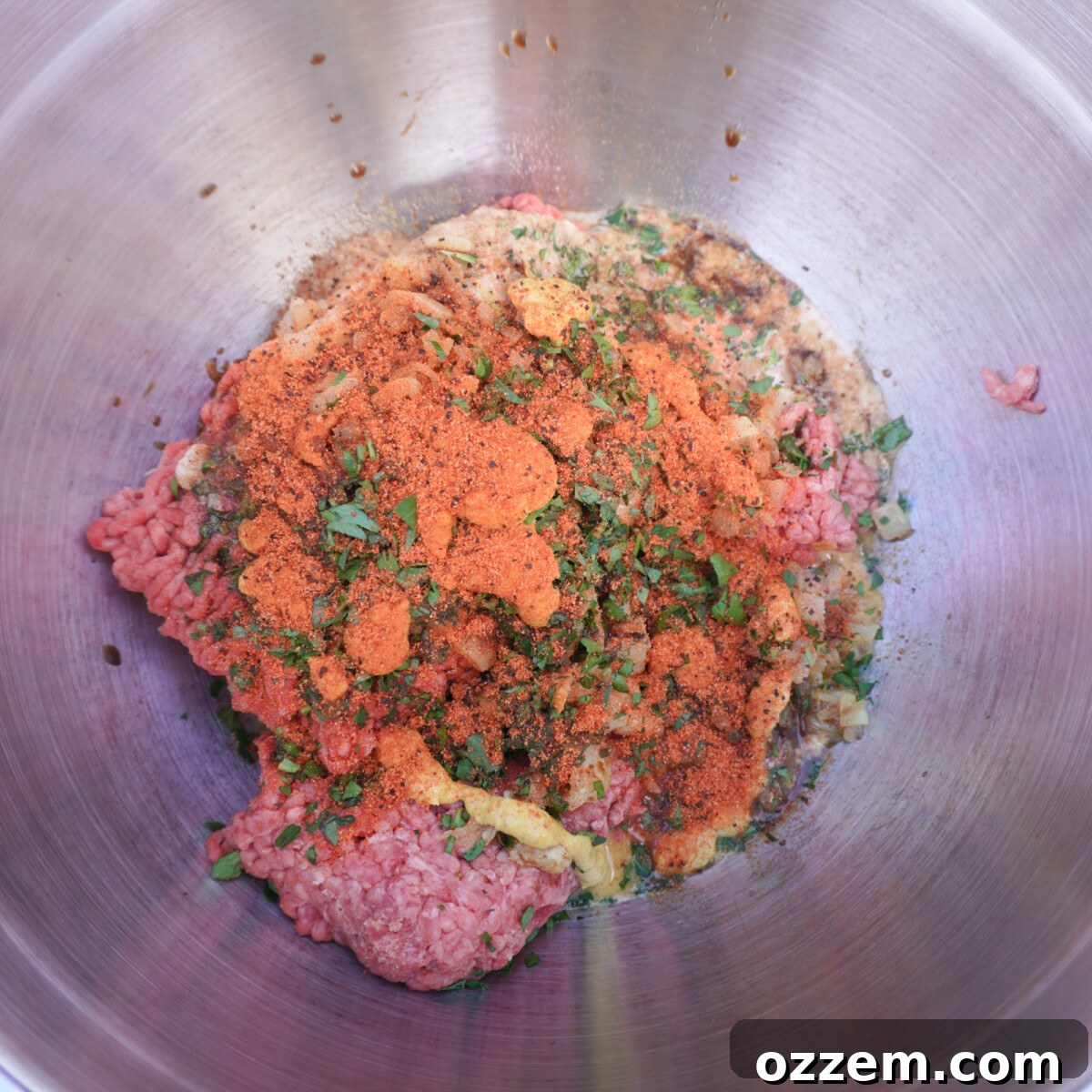 Raw meatloaf mixture with all ingredients combined in a metal mixing bowl.