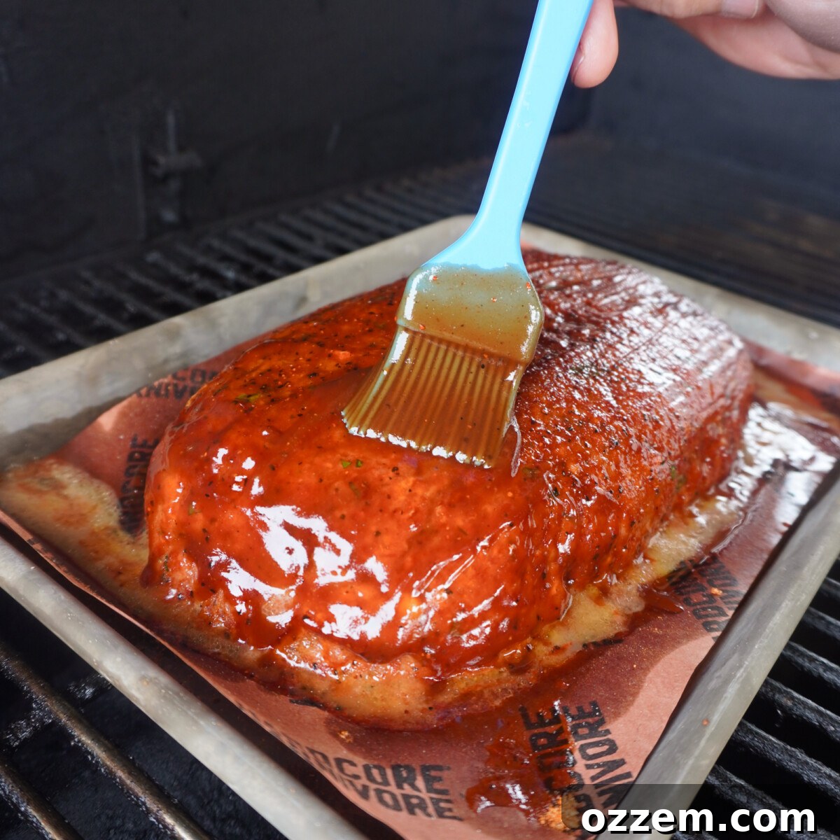 Applying a delicious glaze to the meatloaf on the grill while it smokes.