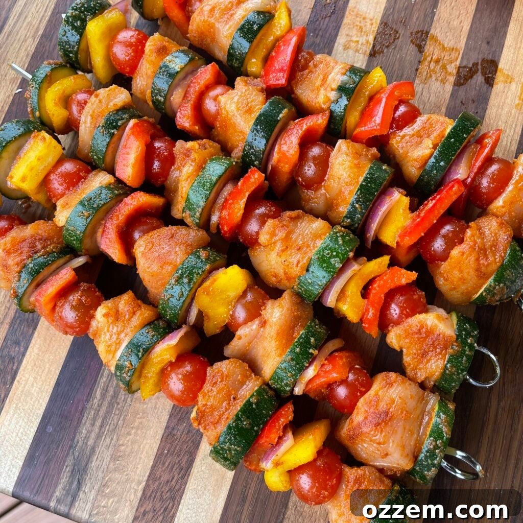 Spicy chicken and vegetable skewers grilling on a barbecue, with a delicious caramelization forming on the chicken and vegetables.