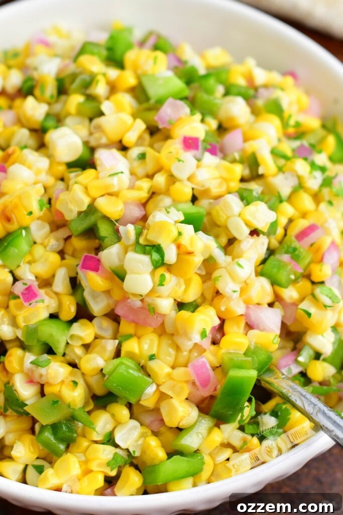 closeup of a spoon scooping out some grilled corn salad out of a white bowl