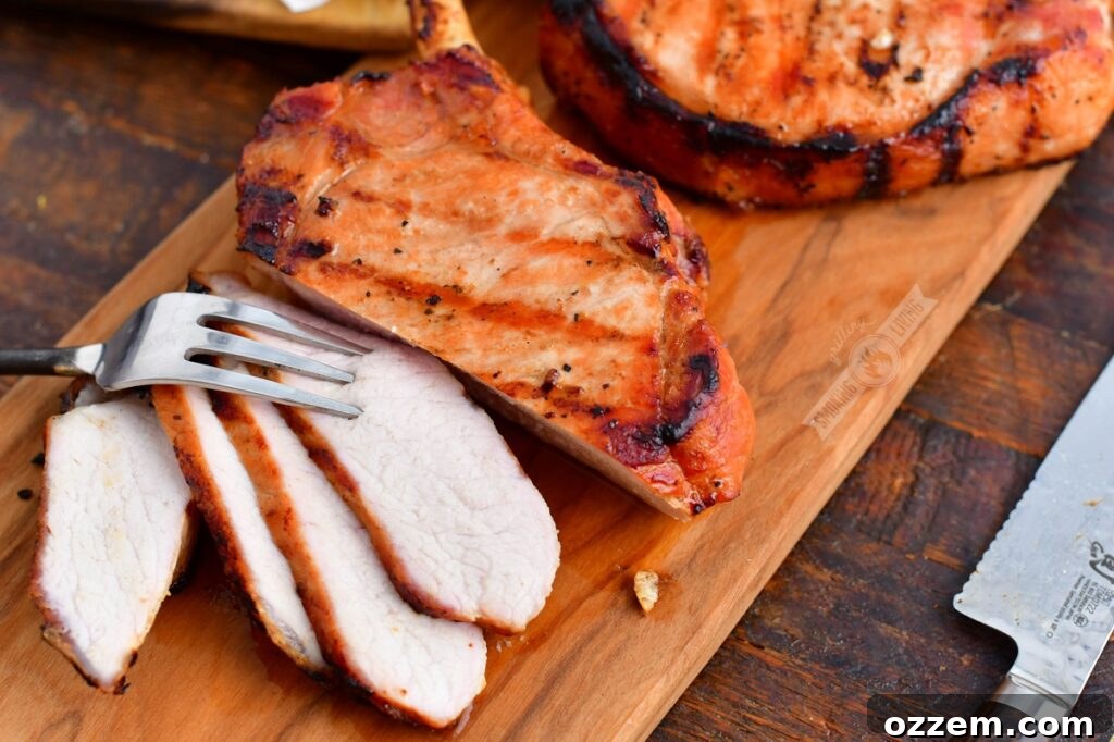 A close-up of a sliced grilled pork chop on a cutting board, showing its juicy texture.