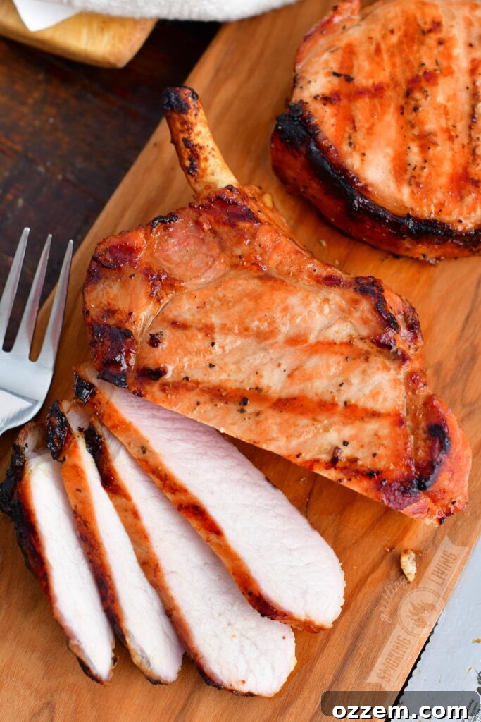 A close-up of a sliced grilled pork chop on a cutting board, ready to be served.
