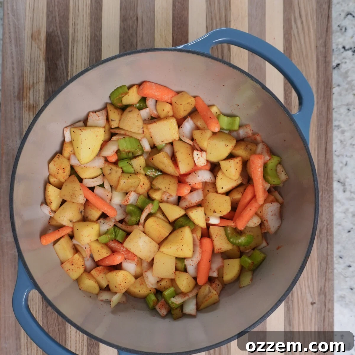 Chopped yellow potatoes, carrots, celery, and onions in a Dutch oven, seasoned and ready for braising.
