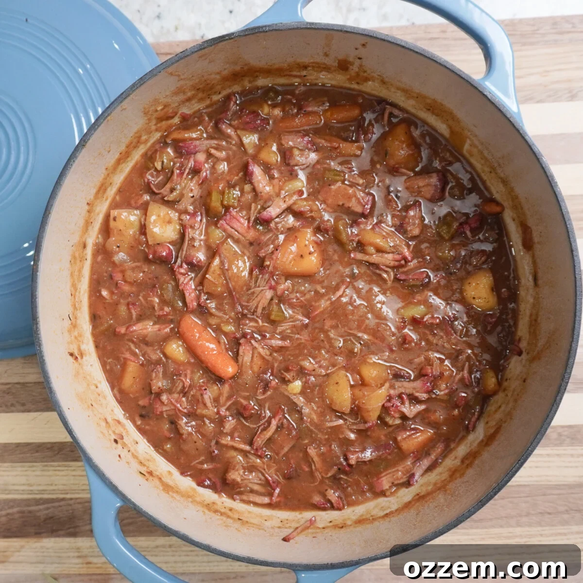 Finished easy pot roast dinner in a Dutch oven, with shredded beef, vegetables, and thick gravy.