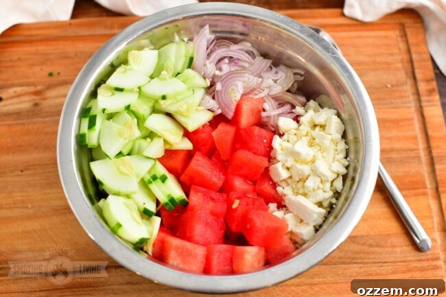 Summer Watermelon Feta Delight 6 Cubed watermelon, sliced cucumbers, and minced shallots in a large mixing bowl, ready to be combined.