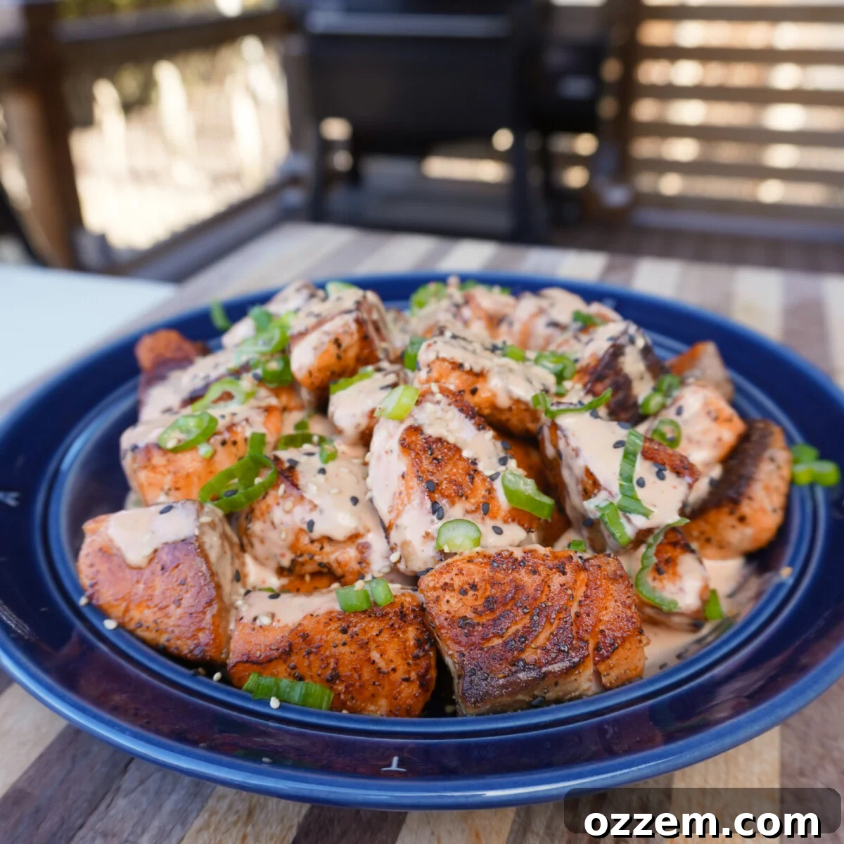 Golden Cajun Salmon Poppers 2 Crispy Cajun Salmon Bites with Bang Bang Sauce, garnished with green onions and sesame seeds.