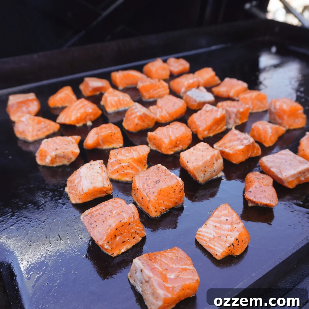 Golden Cajun Salmon Poppers 8 Cajun salmon bites cooking on a hot griddle.
