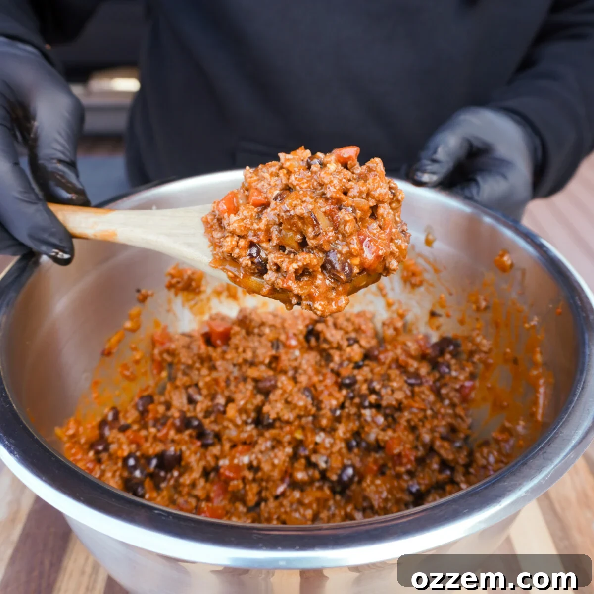 A wooden spoon scooping up a hearty portion of the rich and flavorful beef enchilada filling, ready for assembly.