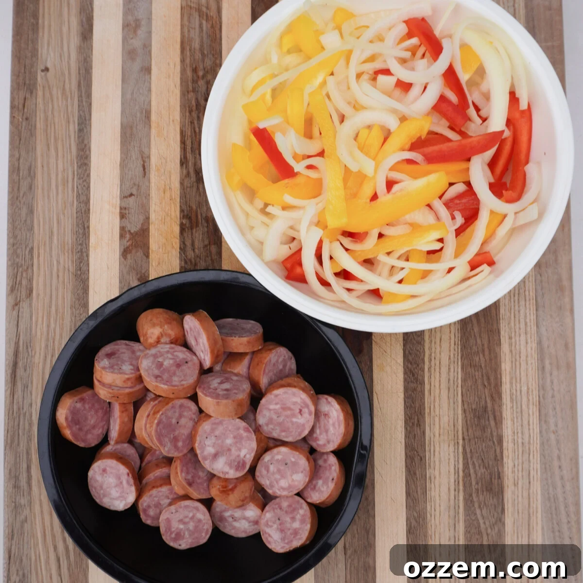 Carefully sliced bell peppers, onions, and smoked sausage laid out, ready for grilling, showcasing fresh ingredients prepared for an easy dinner.