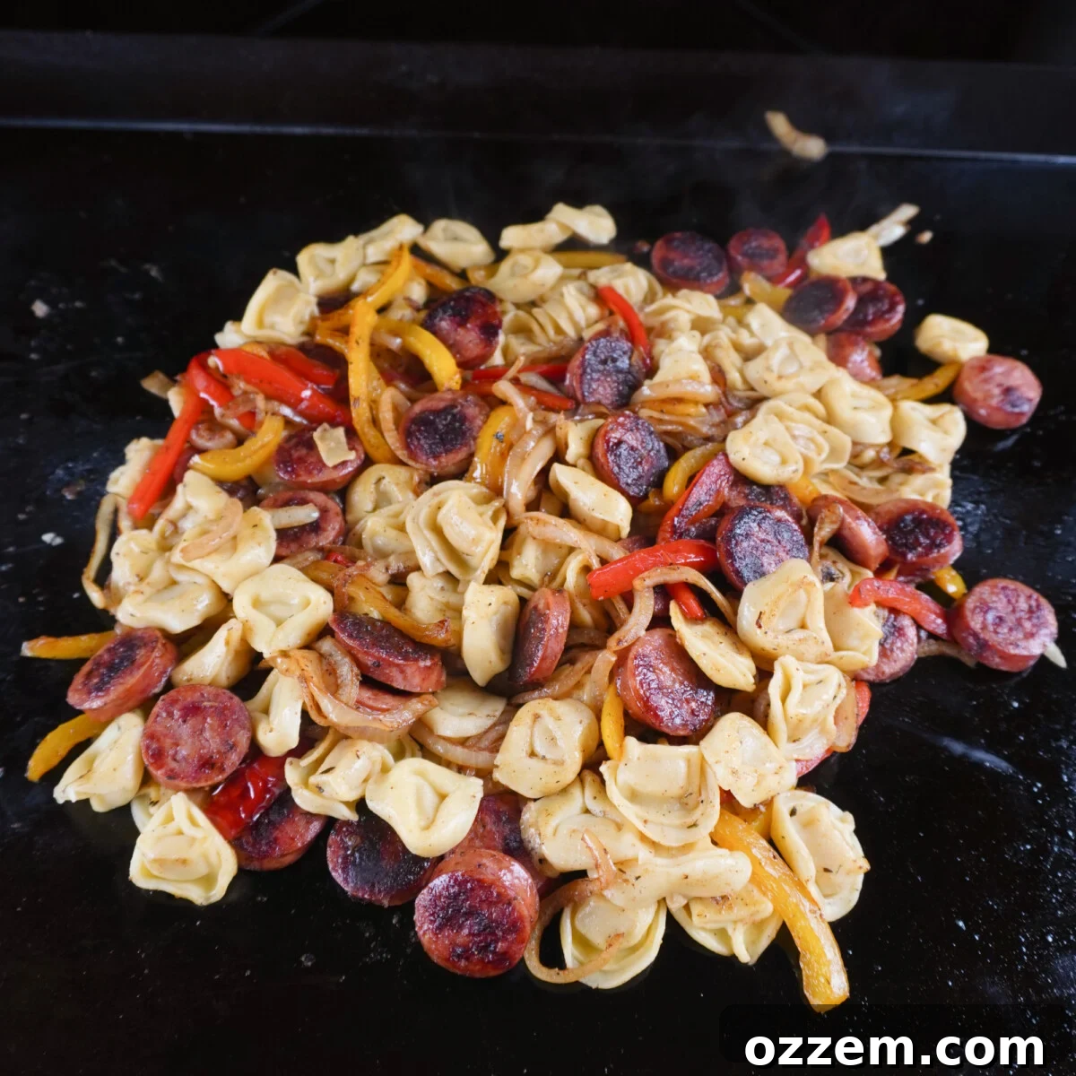 The vibrant medley of grilled sausage, sautéed vegetables, and perfectly steamed tortellini, tossed together on the griddle for a flavorful weeknight dinner.
