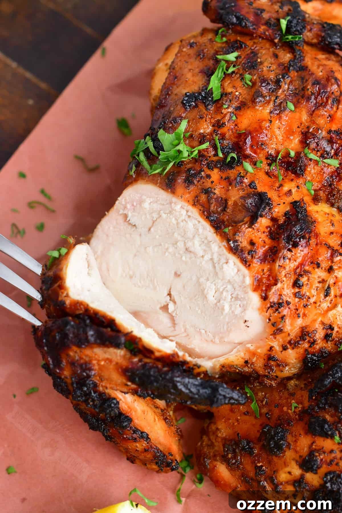 closeup of perfectly sliced chicken breast from the grilled whole chicken, revealing its juiciness