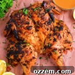 top view of grilled spatchcock chicken on butcher paper, ready to be carved