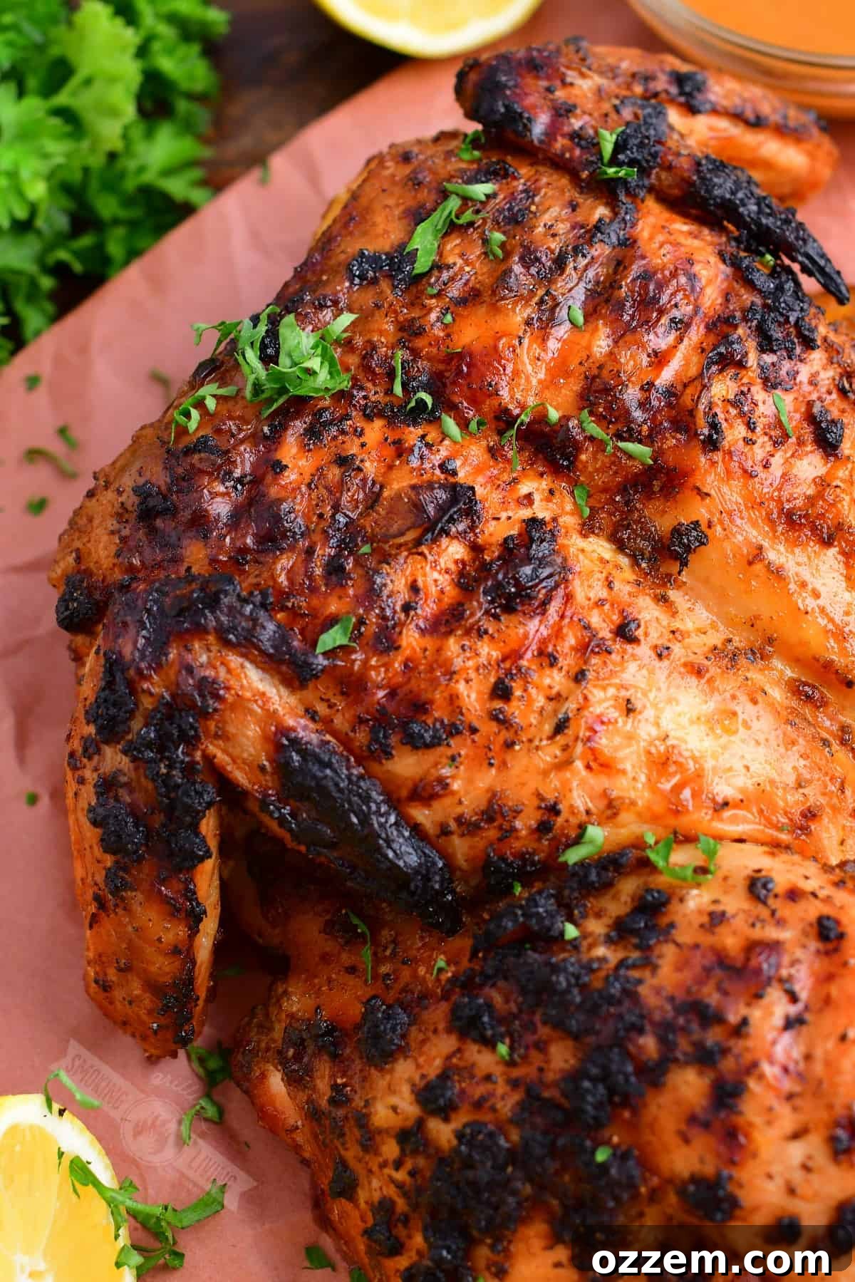 closeup of grilled whole chicken with fresh parsley garnish, ready to be served