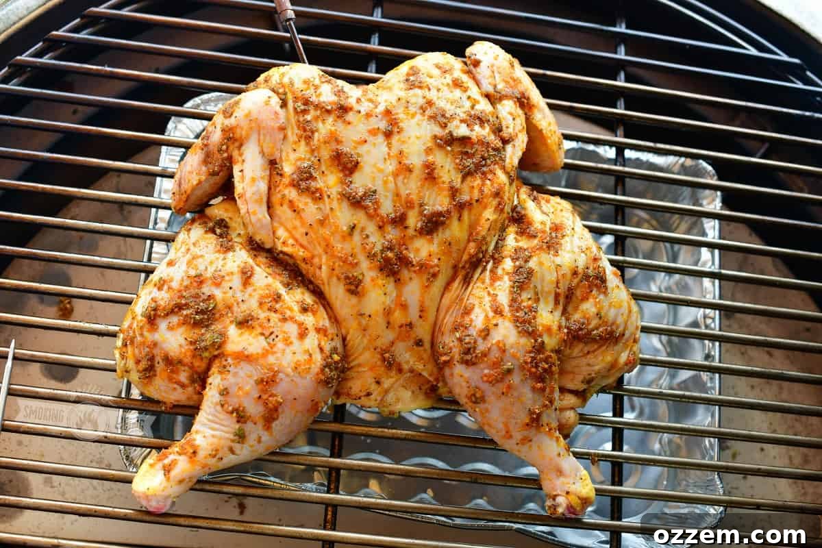 uncooked spatchcocked chicken on the grill over indirect heat with a drip pan underneath
