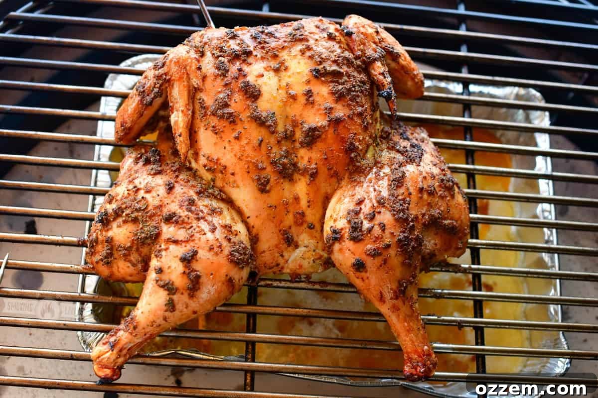 spatchcock chicken cooking on the grill with drip pan underneath, lid closed for even heating