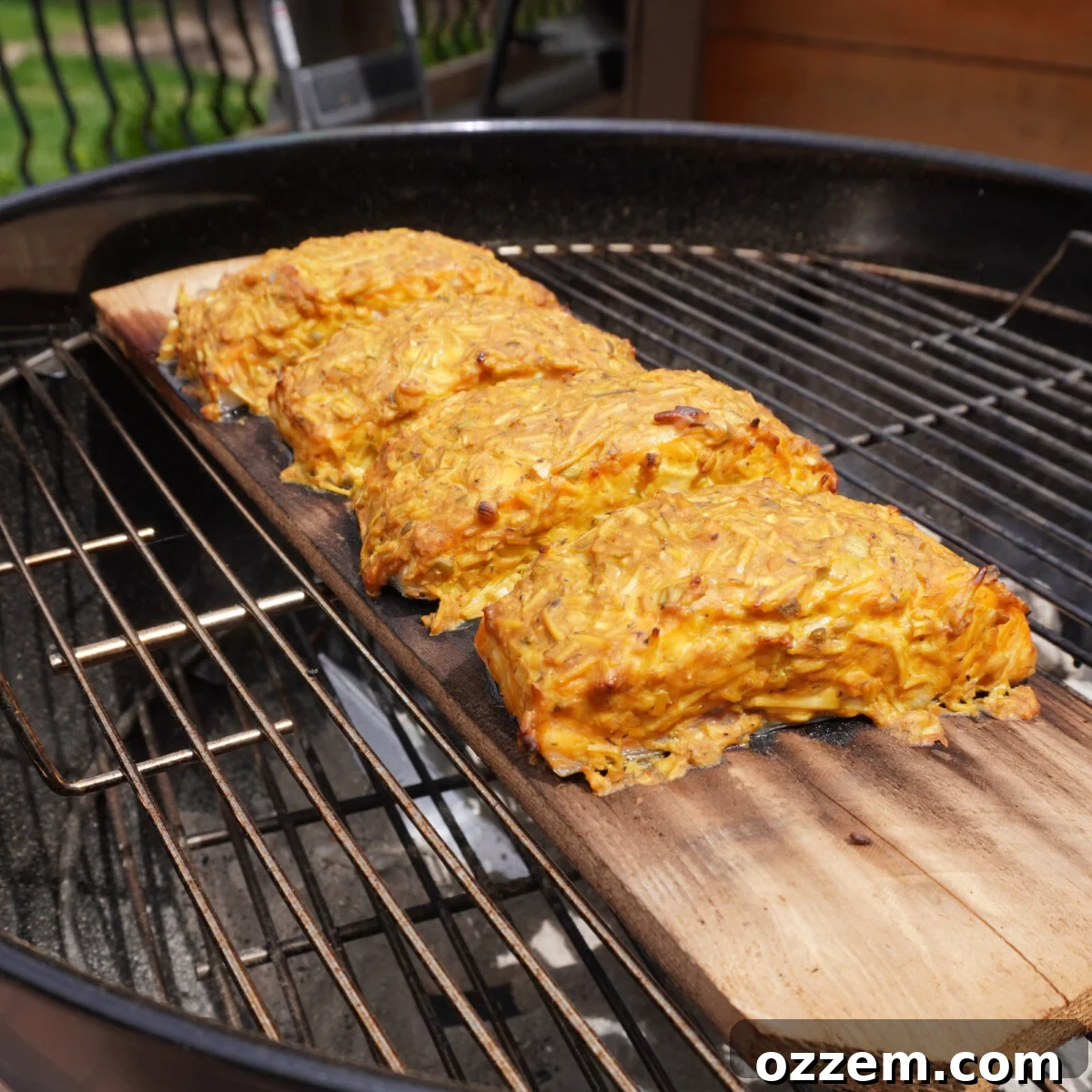 Grilled salmon with dill mustard sauce on a cedar plank, cooking on the grill.