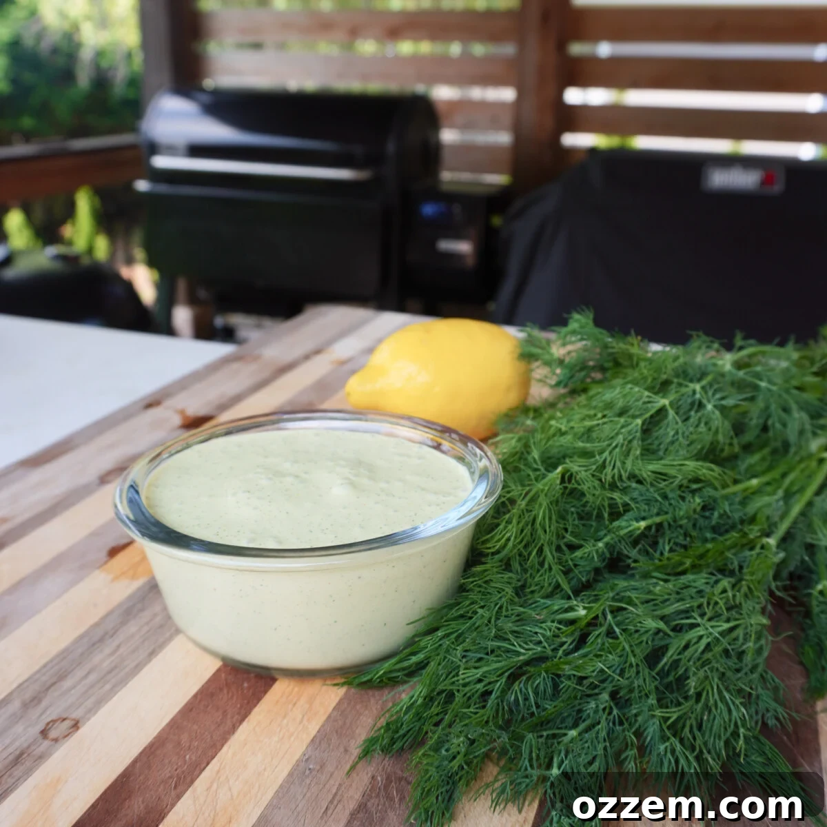 A bowl of creamy lemon dill sauce garnished with fresh dill sprigs, ready for dipping.