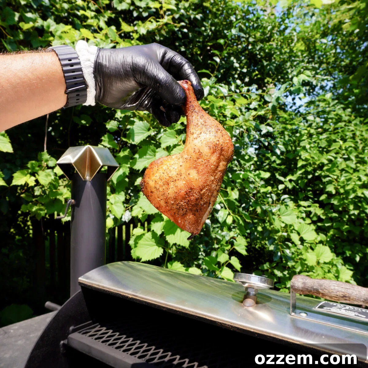 Close-up of a sweet tea brined smoked chicken quarter on a serving board, garnished.