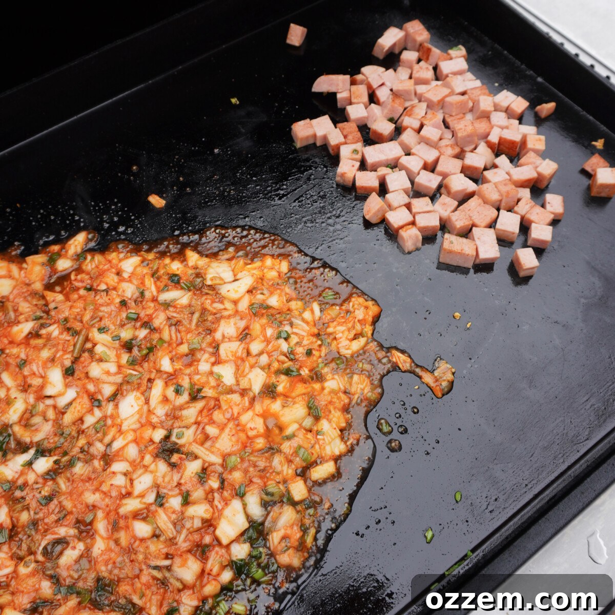 Ingredients for kimchi fried rice separated and cooking on a hot griddle.