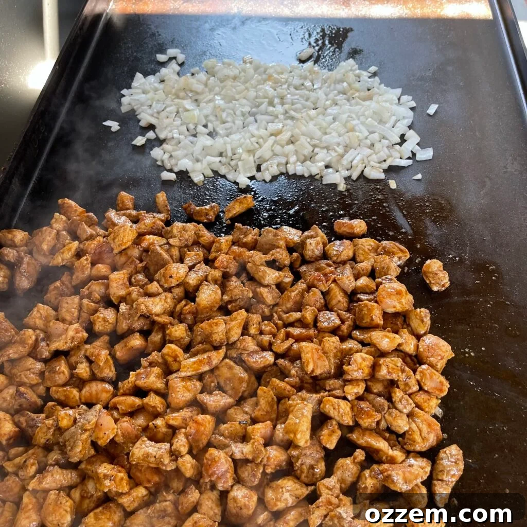 Chicken and onions cooking on a hot griddle, preparing for fried rice