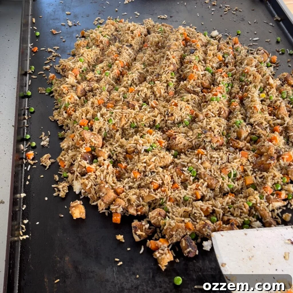 The full chicken fried rice mixture, including eggs and vegetables, cooking on the griddle