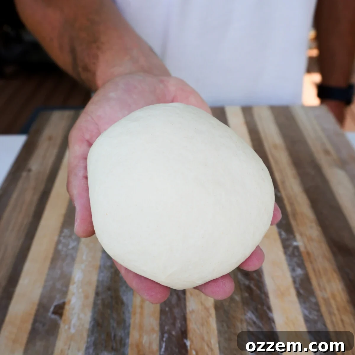 Freshly kneaded homemade pizza dough resting in a mixing bowl, ready for its first rise.