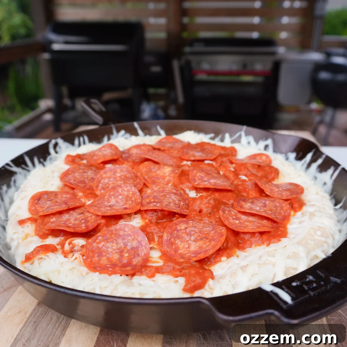 A cast iron pizza fully loaded with cheese, sauce, and pepperoni, ready for its final bake in the oven.