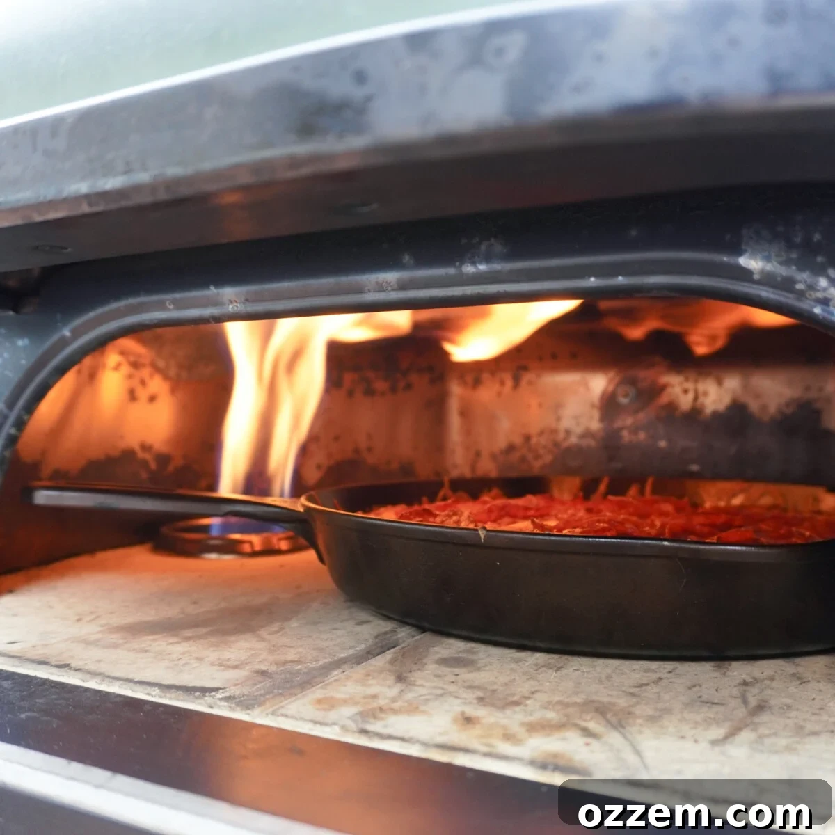 A perfectly cooked easy cast iron pizza baking in a pizza oven, cheese bubbling and crust turning golden.