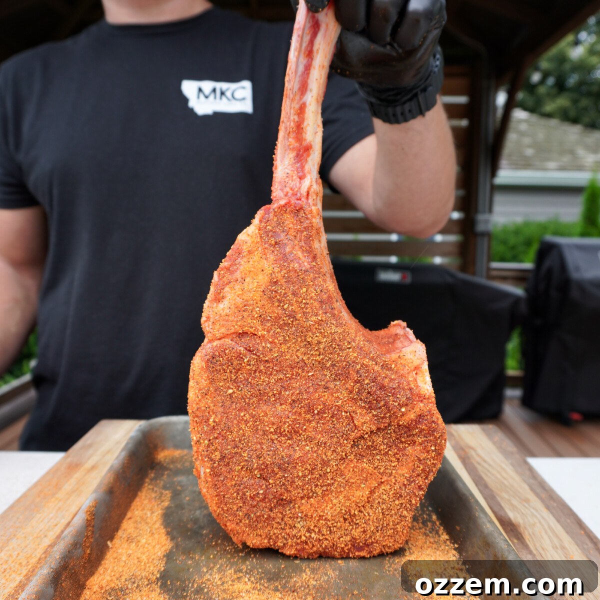Sizzling Tomahawk with Zesty Cajun Butter 4 Tomahawk steak generously seasoned with Cajun honey rub, standing upright.