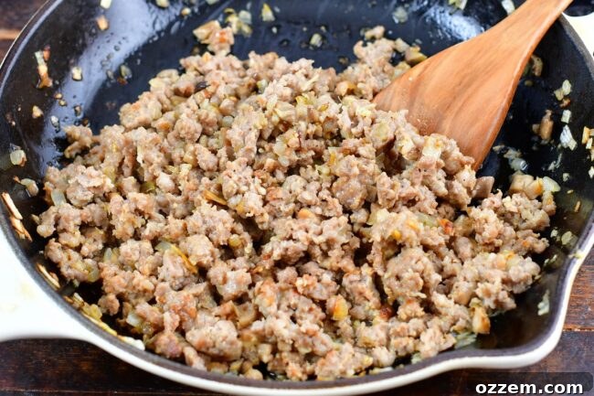 Sautéed Italian sausage, diced onions, and mushroom stems cooking in a pan.