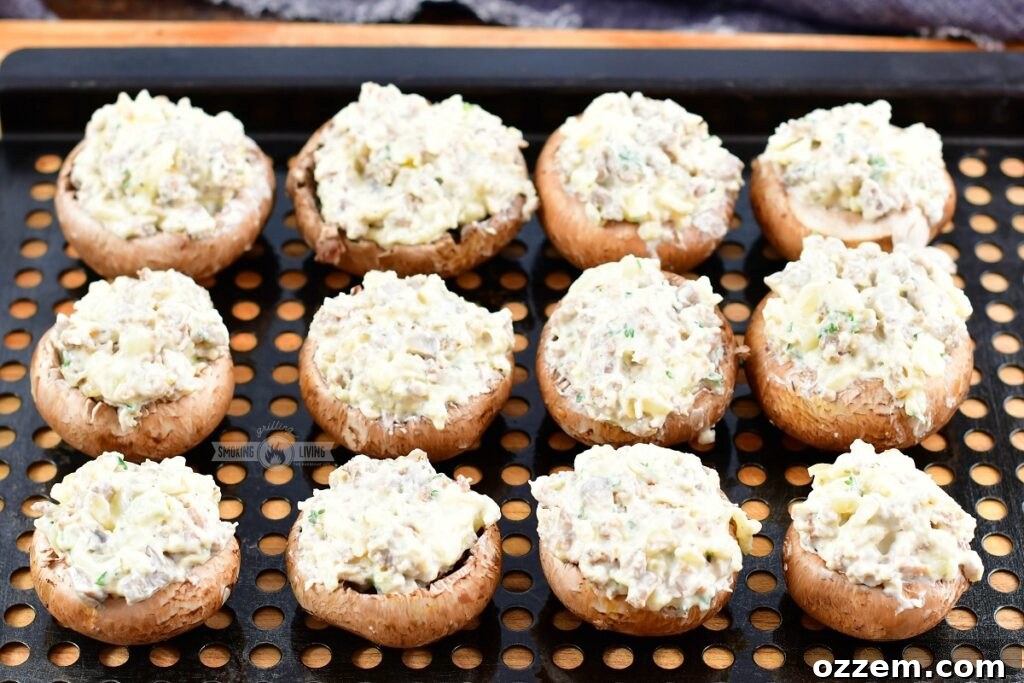 Stuffed mushrooms arranged neatly on a metal grilling tray, ready for the smoker.