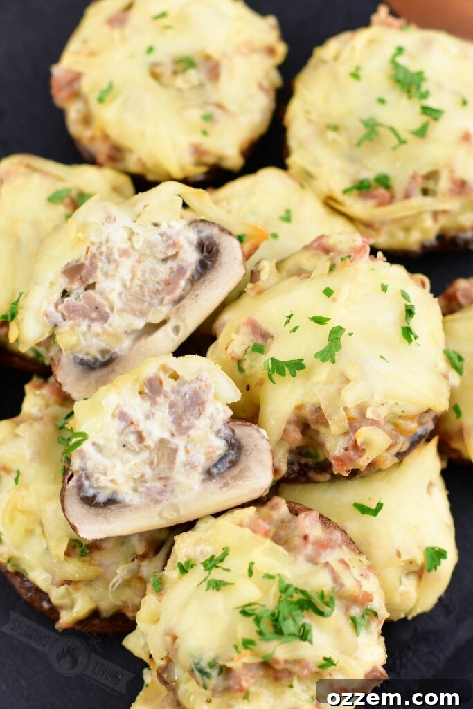 A smoked stuffed mushroom cut in half, showcasing the rich filling, on a plate with other whole mushrooms.