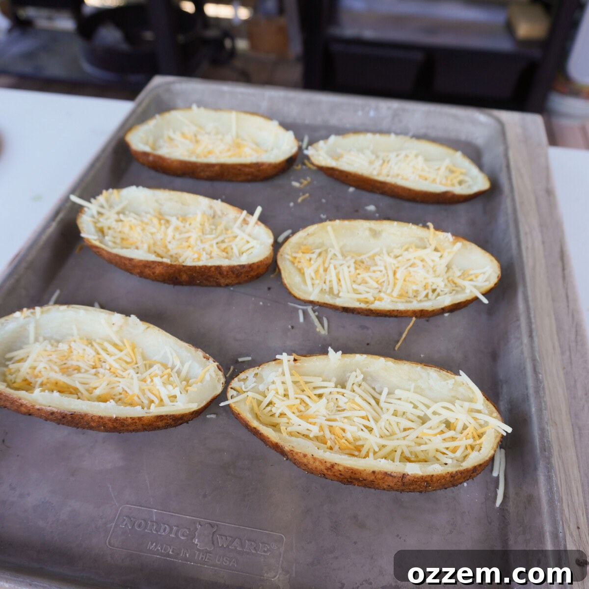 Empty potato skins with a layer of shredded cheese at the bottom.