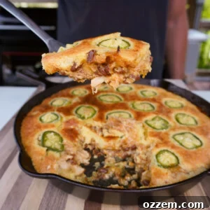 A delectable slice of BBQ Chicken Cornbread Casserole, showcasing the perfectly baked layers of golden cornbread, tender chicken, and rich baked beans in a rustic cast iron skillet.