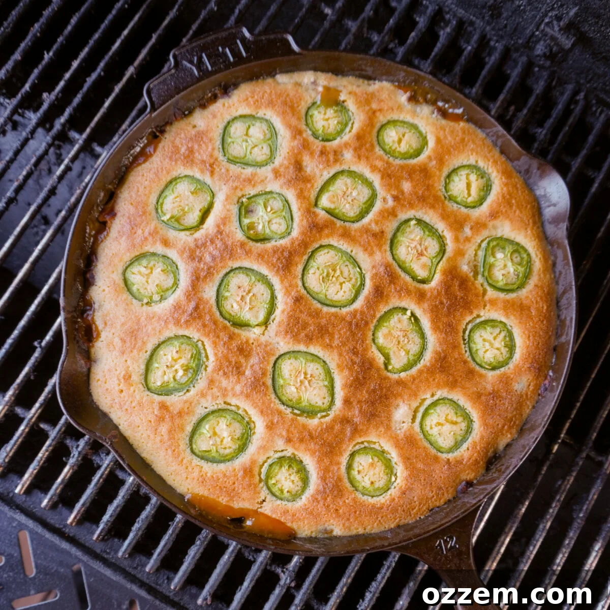 The BBQ Chicken Cornbread Casserole beautifully baking on a pellet grill, with a glimpse of the smoky interior, hinting at the rich, infused flavor being developed.